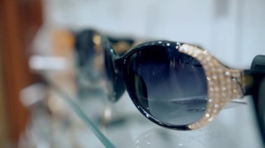 Güneş gözlüğü. Moda gözlüklerinin farklı modelleri olan bir vitrin. Yakın plan. Gözlük. Alışveriş. Perakende mağazasından güneş gözlüğü almak. Optik dükkanı. 