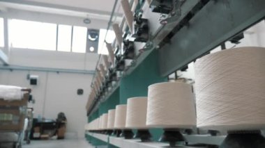 Tekstil fabrikası. İplik yapma süreci. İplik üretimi. Dönen yapım. Tekstil fabrikası ekipmanı. Fabrika makineleri makaraları ya da pamuklu ya da yün ipliklerle bobinleri geri sarıyor. Yakın plan.