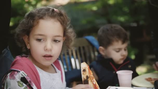 Mała Słodka Kręcona Dziewczyna Zjada Kawałek Pizzy Pikniku Dla Dzieci — Wideo stockowe