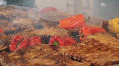Yanan kömürlerin üzerinde ızgara et. Izgara sebze. Yakın plan. Kızarmış kaburgalar ve sulu kırmızı biberler kömürün üzerinde barbekü ızgarasında kızarıyor. Izgarada pişmiş yemek. Açık havada yemek yapmak..
