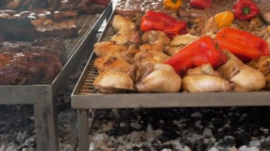 Yanan kömürlerin üzerinde ızgara et. Izgara sebze. Yakın plan. Kızarmış kaburga, büyük parça domuz boynu, tavuk eti, sosis halkaları. Büyük kırmızı biberler kömürün üzerinde barbekü rafında kızarıyor.. 