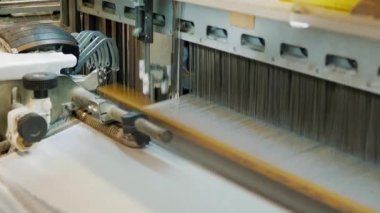 Dokuma makinesi. Yakın plan. Bir tekstil fabrikasında endüstriyel dokuma tezgahı makinesi çalışıyor. Dokuma kumaşı endüstriyel bir makine tarafından serbest bırakılıyor. Dokuma. kumaş üretimi
