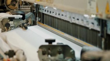 Dokuma makinesi. Yakın plan. Bir tekstil fabrikasında endüstriyel dokuma tezgahı makinesi çalışıyor. Dokuma kumaşı endüstriyel bir makine tarafından serbest bırakılıyor. Dokuma. kumaş üretimi