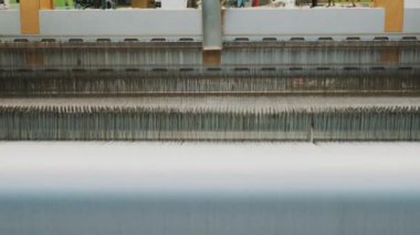 Dokuma makinesi. Yakın plan. Bir tekstil fabrikasında endüstriyel dokuma tezgahı makinesi çalışıyor. Dokuma kumaşı endüstriyel bir makine tarafından serbest bırakılıyor. Dokuma. kumaş üretimi