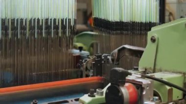 Dokuma makinesi. Yakın plan. Bir tekstil fabrikasında endüstriyel dokuma tezgahı makinesi çalışıyor. Dokuma kumaşı endüstriyel bir makine tarafından serbest bırakılıyor. Dokuma. kumaş üretimi
