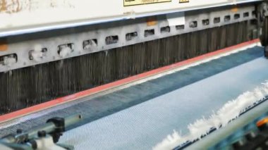 Dokuma makinesi. Yakın plan. Bir tekstil fabrikasında endüstriyel dokuma tezgahı makinesi çalışıyor. Dokuma kumaşı endüstriyel bir makine tarafından serbest bırakılıyor. Dokuma. kumaş üretimi