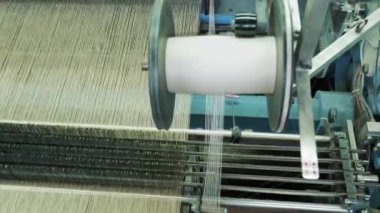 Tekstil fabrikasında dokuma tezgahı. Yakın plan. Çalışma süreci. Beyaz iplikli büyük bir makara. Fabrika mekanizması ipliklerden kumaş dokuyor. Tekstil endüstrisi. Dokuma fabrikası. kumaş üretimi.