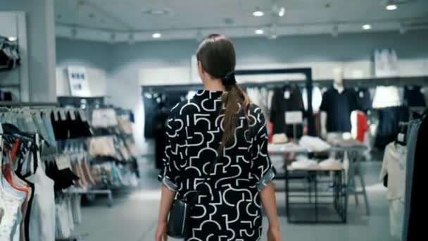 Shopping Purchases Teenage Girl Walks Clothing Store Rows Clothes Looks — Stock Video