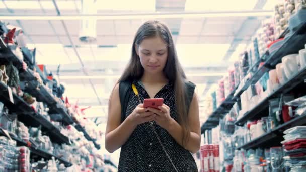 携帯電話を使って ショッピングモールに立っている顧客 携帯電話を見て ブラウジング 読書メッセージ ショッピングモールで時間を過ごす十代の少女 — ストック動画