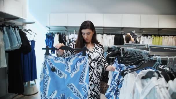 Compras Compras Uma Jovem Morena Escolhe Novas Roupas Elegantes Prateleiras — Vídeo de Stock