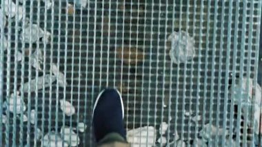 Asma köprü. Yakın plan. Spor ayakkabılı bir turistin bacakları bir dağ nehrinin üzerinde, boş metal asma köprü boyunca yürüyor. Yaz günü. seyahat ve macera