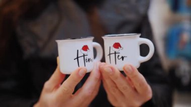 Noel alışverişi. Noel süsleri. Yakın plan. Bayramlık kahve fincanları kadınların elinde. Noel 'de aile ve arkadaşlar için hediyeler seçip almak. Neşeli bir atmosfer. Noel