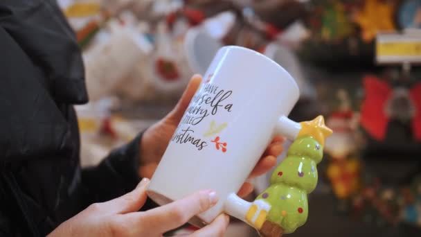 クリスマスの装飾 ショッピング クローズアップ 女性の手でカップ クリスマス前に家族や友人のための贈り物を選択して購入します お祝いする雰囲気 クリスマスフェア メリークリスマスとハッピーニュー — ストック動画