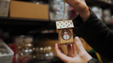 Noel ağacı oyuncağı. Yakın plan. Noel süsü, ev şeklinde oyuncak fener, kardan adam. Noel öncesi alışveriş mağazası, panayır, süpermarket ya da alışveriş merkezi. Arka plan bulanık. Ruhu