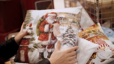 Noel dekoratif yastıkları. Noel aksesuarları. Alışveriş. Yakın plan. Bayramlık aksesuar seçen ve satın alan bir kadın, kış tatili için bir mağazada dekoratif yastıklar, adil, süpermarket veya