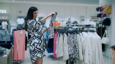 Alışveriş. Satın alma. Genç bir esmer kadın, mağazadan ya da pazar yerinden yeni şık kıyafetler seçiyor. Alışveriş merkezi. Moll. Süpermarket. İndirim, indirim. 