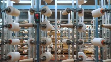 İplik makaraları. Endüstriyel tekstil fabrikasının atölyesi. Bir sürü iplik makarası olan raflar. Daha fazla kumaş üretimi için ipliklerin boyanıp kurutulması. Dokuma fabrikası. Tekstil endüstrisi. Dokuma tezgahları