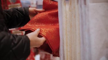 Noel süsleri, aksesuarlar. Alışveriş. Yakın plan. Kadın Noel 'e kadar bir mağaza, mağaza, fuar, süpermarket veya alışveriş merkezinde Noel masası için şenlikli bir masa örtüsü seçer.