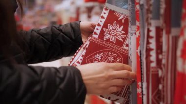 Noel süsleri, aksesuarlar. Alışveriş. Yakın plan. Kadın Noel 'e kadar bir mağaza, mağaza, fuar, süpermarket veya alışveriş merkezinde Noel masası için şenlikli bir masa örtüsü seçer.