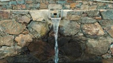 Bir dağ pınarı. Hayvanlar için içme suyu. Taş bir şelale. Dağ pınarından suyla dolu bir çukur. İçilebilir suyu olan metal bir çeşme. Yüksek kalite 4k görüntü