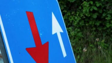 Trafik levhası. Kırmızı ve beyaz okları olan mavi kare. Yol çalışması tabelası. Yakın plan. Tamir çalışmaları yolda devam ediyor. Dikkat! Yol tamiri. Alp dağlarında büyük bir köprü. yaz günü 