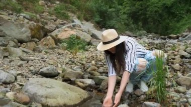 Alp dağlarındaki bir dağ nehrinden temiz su içen bir kız. Ekoloji. Turizm ve yürüyüş. Boş zaman. Sağlıklı bir yaşam tarzı. Yüksek kalite 4k görüntü