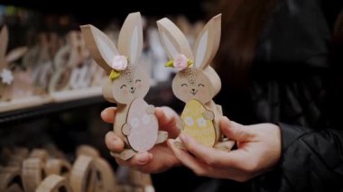Paskalya panayırı. Yakın plan. Paskalya süslerini tutan kadın elleri. Paskalya tavşanlarının komik figürleri. Katolik Paskalyası için geleneksel Avrupa dekorasyonu