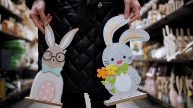 Paskalya panayırı. Yakın plan. Paskalya süslerini tutan kadın elleri. Paskalya tavşanlarının komik figürleri. Katolik Paskalyası için geleneksel Avrupa dekorasyonu