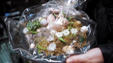 Paskalya panayırı. Yakın plan. Paskalya süslerini tutan kadın elleri. Paskalya kompozisyonu, saydam ambalajda bir tavşan ve yumurta. Katolik Paskalyası için geleneksel Avrupa dekorasyonu 