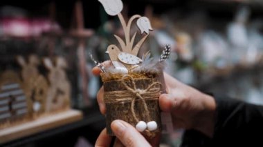 Paskalya indirimi. Yakın plan. Güzel bir Paskalya süslemesi tutan dişi eller, bir kuş, yumurta ve çiçeklerle kompozisyon. Paskalya dekoru alışverişi. Paskalya süsleri ve hediyeler dükkanda.