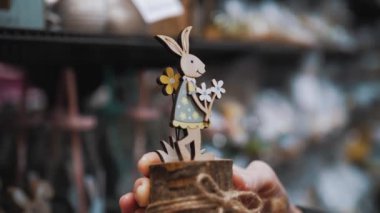 Paskalya panayırı. Yakın plan. Paskalya süslerini tutan kadın elleri. Paskalya tavşanının komik biblosu. Katolik Paskalyası için geleneksel Avrupa dekorasyonu