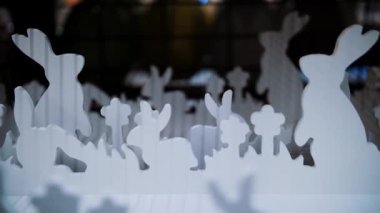 Paskalya panayırı. Yakın plan. Çimlerin üzerinde kontrplaktan yapılmış Paskalya tavşanlarının dekoratif beyaz heykelcikleri bir mağazada sergileniyor. Geleneksel Avrupa paskalya dekoru ve dekorasyonları. 