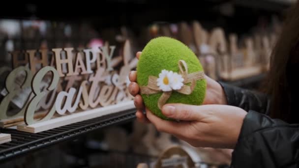 复活节展会 女性的手拿着一个有趣的绿色复活节彩蛋的雕像 传统的欧洲牡蛎装饰和装饰 复活节购物 陈列在商店里 — 图库视频影像