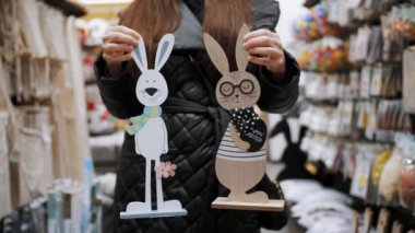 Paskalya panayırı. Yakın plan. Paskalya süslerini tutan kadın elleri. Paskalya tavşanlarının komik figürleri. Katolik Paskalyası için geleneksel Avrupa dekorasyonu