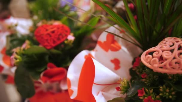 ハッピーバレンタインデー クローズアップ バレンタインデーのロマンチックな贈り物として 真ん中の赤またはピンクのハートのフィギュアを持つお祝いのパッケージで花の花束 — ストック動画