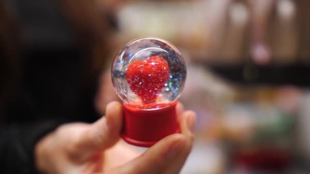 ハッピーバレンタインデー クローズアップ 手元に 中に赤いハートと虹が輝くガラスボール 感情と愛の表現として バレンタインデーのためのロマンチックな贈り物 各種ギフトの販売 — ストック動画
