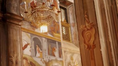 Lüks bir kristal avize, zengin dekore edilmiş freskler ve klasik ahşap mimariyle çevrili, zarif ve savurgan bir şekilde bir Avrupa kilisesinin salonunda asılı duruyor.