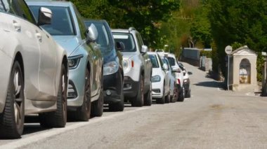 Park yeri. Park halindeki arabalar güneşli bir günde yol kenarına dizilir. Yüksek kalite 4k görüntü