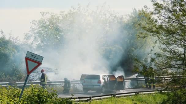 Bomberos Dedicados Controlan Incendio Vehicular Una Carretera Rodeados Humo Exuberante — Vídeo de stock
