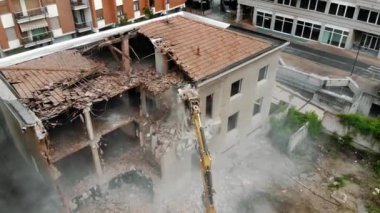 Şehir ortamındaki büyük bir kazıcı tarafından yıkılan yıkık dökük eski bir binanın ayrıntılı görünümü, yeniden yapılanma ve kentsel dönüşümü sembolize ediyor