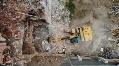 Bir kazıcının moloz, tuğla ve sökülmüş malzemeler, inşaat ve kentsel kalkınma temaları ile çevrili olduğu kentsel bir bölgedeki bir yıkım alanını gösteren hava görüntüleri