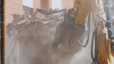 BIELLA, İtalya, 25 Nisan 2024: Fotoğraf, toz ve enkaz ile çevrili, çarpıcı bir kentsel yenilenme sahnesini gösteren eski bir binayı yıkan endüstriyel bir kazıcıyı resmediyor