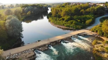 Şelaleden bir Weir 'ın hava görüntüsü. Küçük Barajı olan Huzurlu Nehir, Yeşillik ile çevrili. Gün batımında nehrin üzerindeki beton köprü. Yüksek kalite 4k görüntü