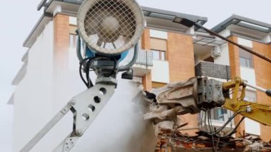 Hidrolik makineli bir şehir binasının yıkılışını gösteren detaylı bir çekim. Güçlü bir kazıcı kolu da dahil olmak üzere ekipman, bir yapıyı sökme işlemi sırasında yakalanır.