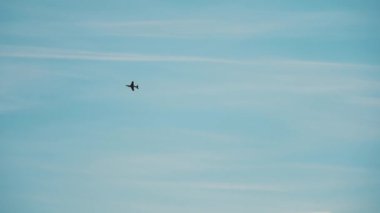 Uçsuz bucaksız mavi gökyüzünde ince bulutlar tarafından vurgulanmış yalnız bir uçak. Görüntü özgürlük ve seyahatin cazibesini çağrıştırıyor.
