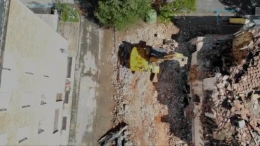 Fotoğrafta yıkım sahasının ortasında bir kazıcı yer alıyor. Etrafı enkazlarla çevrili, kentsel yenilenme sürecini havadan perspektif, inşaat ve yıkım temaları altında yakalıyor.