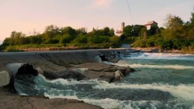 Weir Şelalesi. Küçük Barajı olan Huzurlu Nehir, Yeşillik ile çevrili. Gün batımında nehrin üzerindeki beton köprü. Yüksek kalite 4k görüntü