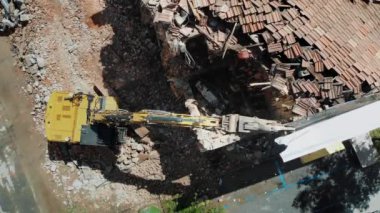 Bir yıkım sahnesinin hava perspektifinde, şehir merkezindeki yıkım ve yeniden yapılanma karışımını gösteren bir kazı makinesinin şehir alanındaki enkazı temizlediği yer.