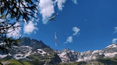 Açık bir günde dağlık arazide bir helikopter. Çevre, vahşi doğa ve kurtarma operasyonları için ideal. Helikopter, yükseklerde malzeme taşımaya yardımcı olur.