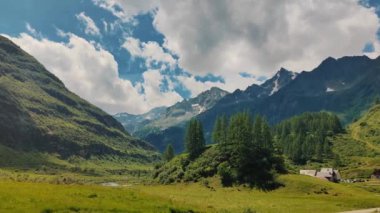 Huzurlu bir Alp Vadisi 'ndeki engebeli dağların altında yemyeşil çayırlar yayıldı. Dağınık bulutlu sakin bir gökyüzü bu doğal manzaranın huzur veren güzelliğini arttırır.